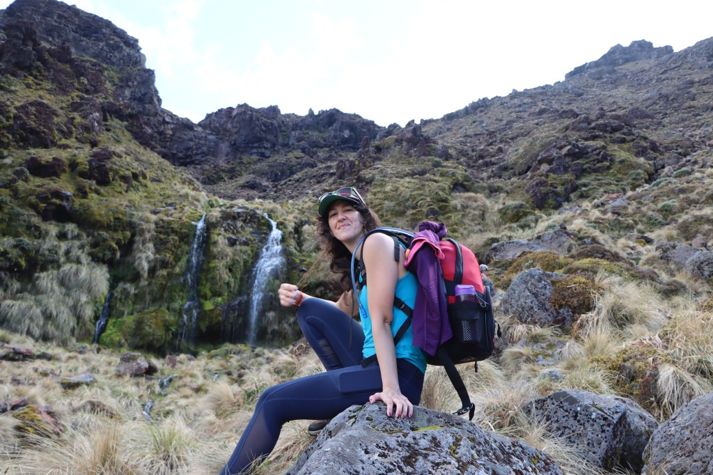 Image of woman with hiking backpack next to waterfall