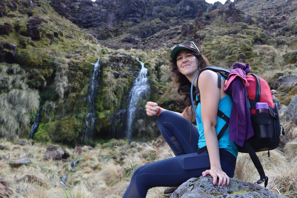 Image of woman with hiking backpack next to waterfall